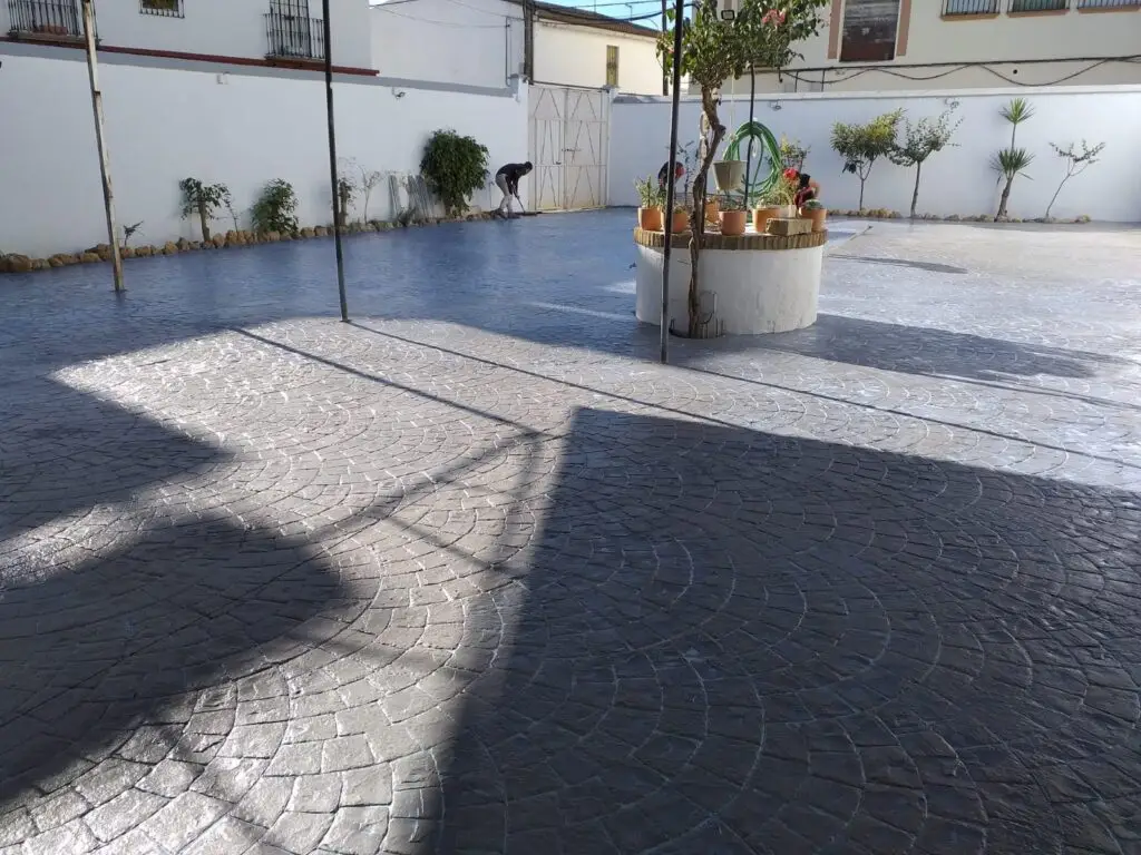 Aplicación de resina protectora para mantenimiento de hormigón impreso en un patio de Sevilla.