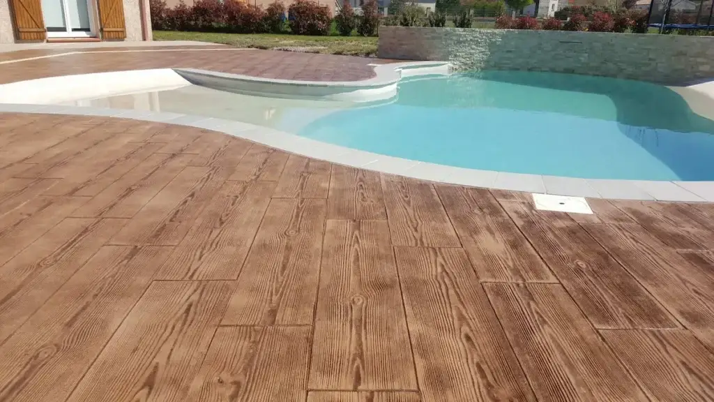 Suelo de patio exterior en Sevilla con hormigón impreso textura madera color nogal, con muebles de jardín encima.