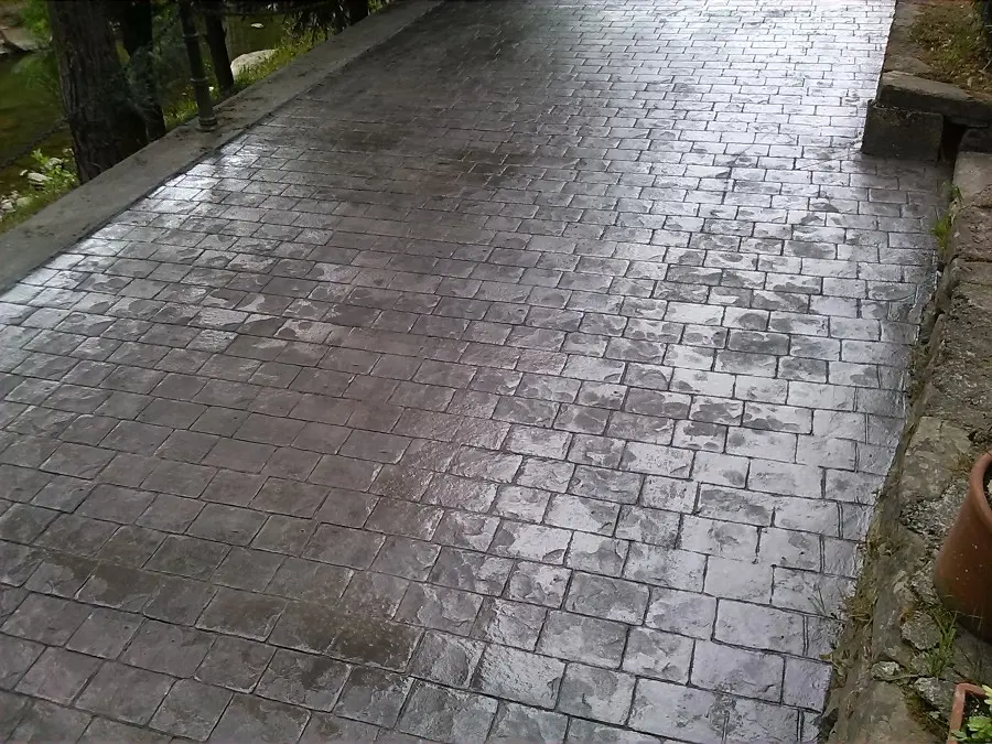 Rampa de garaje de un chalet en el Aljarafe sevillano pavimentada con hormigón impreso gris textura adoquín.